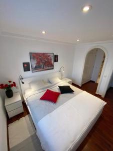 a large white bed with red pillows on it at Appartement 3 chambres, piscine et vue mer in Santa Pola +22 photos