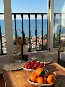 a table with two plates of fruit and a bottle of wine at Appartement 3 chambres, piscine et vue mer in Santa Pola