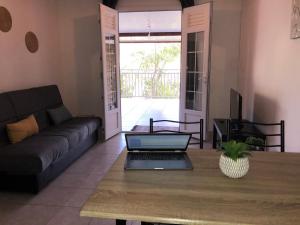 a living room with a couch and a laptop on a table at villa entre ciel et montagne in Le Carbet
