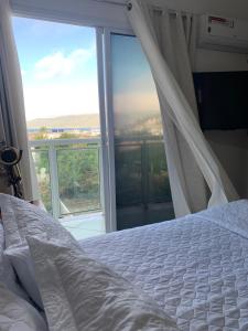 ein Schlafzimmer mit einem Bett und einem großen Fenster in der Unterkunft Ap praia dos anjos com vista in Arraial do Cabo