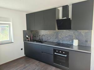 a kitchen with black cabinets and a counter top at Villa AS MOON with pool in Split