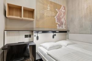 two beds in a room with a desk and a tv at Fyrtøjet - The cheapest hotel in town in Odense