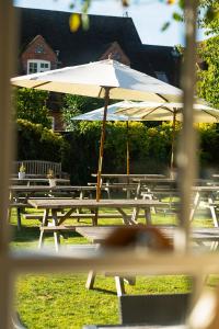 un gruppo di tavoli da picnic con ombrellone di The Stag and Huntsman at Hambleden a Henley on Thames