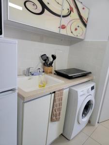 a kitchen with a sink and a washing machine at Last floor apartment with a breathtaking view balcony in Petaẖ Tiqwa