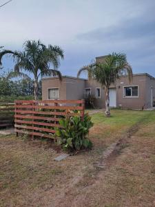a house with a fence and two palm trees at posada acevedo in Acevedo