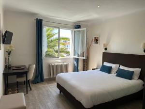 a bedroom with a bed and a window and a desk at Hotel Le Goeland in Barbâtre