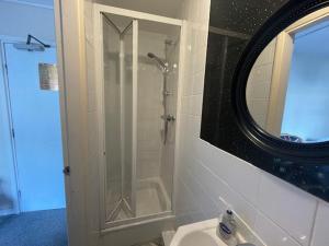 a bathroom with a shower and a sink with a mirror at South Dene Hotel in Bridlington
