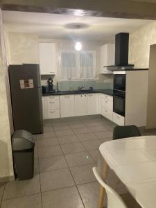una cucina con mobili bianchi e un frigorifero nero di Maison tout confort 6 personnes wifi parking a Colomiers Altre 2 foto