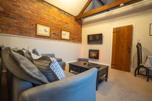 a living room with two couches and a brick wall at Hood Lane Farm - The Parlour - Self Catering Ground Floor Apartment in Arley