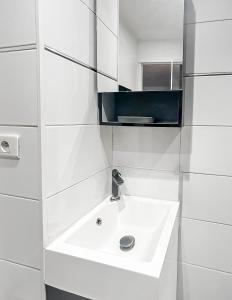 ein weißes Badezimmer mit Waschbecken und Spiegel in der Unterkunft Studio Le Montebello - Vintage, WiFi et Netflix in Fontainebleau