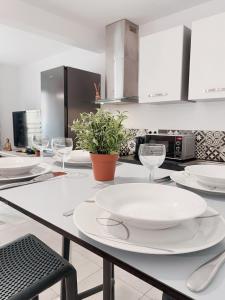 a kitchen with white plates and wine glasses on a table at 2 Chambres avec Balcon en Centre-Ville et Plage au Calme in Canet-en-Roussillon