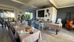 a dining room with tables and a guitar in a room at Hotel Le Goeland in Barbâtre