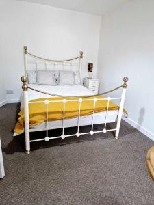 a bedroom with a white bed with a yellow blanket at Large Victorian Townhouse in Buxton
