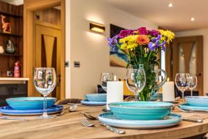 a table with glasses and a vase of flowers on it at Lovely South Downs Town House in Upper Beeding