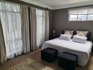 a bedroom with a large white bed and windows at Green Hills Farm House in Drummond