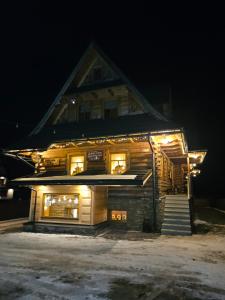 a log cabin with lights on it at night at Apartamenty SKUPNIOWY UPŁAZ in Murzasichle