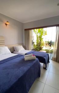 a bedroom with two beds with blue sheets and a window at Pousada Marajoara - Pipa in Pipa +111 photos