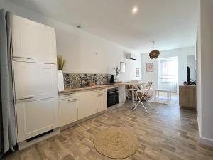 a kitchen with white cabinets and a wooden floor at Le Talia - Terrasse in Auch