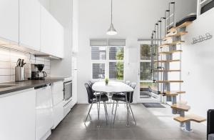 a white kitchen with a white table and chairs at First Camp Grenen Strand in Skagen