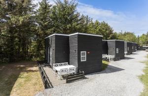 a row of black tiny houses with a bench at First Camp Grenen Strand in Skagen