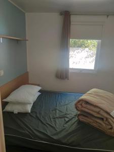 una cama en una habitación con ventana en MOBIL HOME la STEPHANOISE, en Valras-Plage