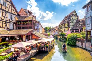 a river with buildings and boats in a city at Gite Traditionnel au Centre Historique d'Éguisheim in Eguisheim