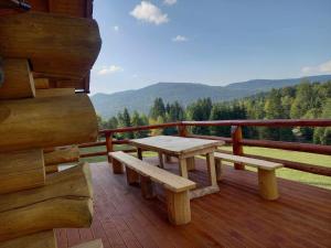 a wooden deck with a table and benches on a balcony at Nyugalom Rönkhàz in Mureş-Sat