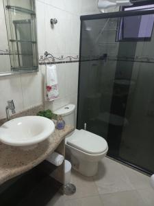 a bathroom with a toilet and a sink and a shower at Apto Aconchegante Piscina 2 Vagas in Guarujá