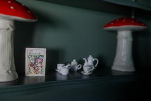 a shelf with two mushrooms and a book and tea sets at Couette & Confitures in Nojeon-le-Sec