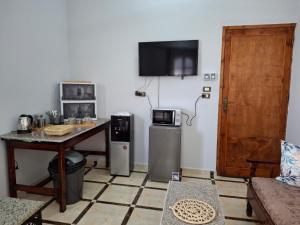 un salon avec une table et une télévision au mur dans l'établissement Ezba Guest House, à Louxor 26 autres photos