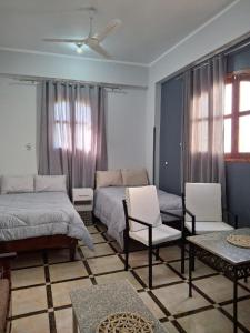 une chambre avec deux lits et un canapé et des chaises dans l'établissement Ezba Guest House, à Louxor