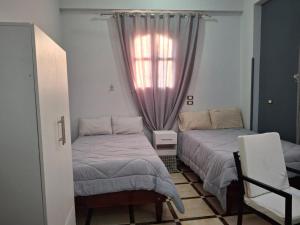 une chambre avec deux lits et une fenêtre dans l'établissement Ezba Guest House, à Louxor