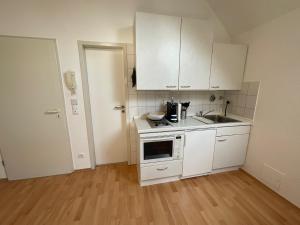 a small kitchen with white cabinets and a sink at Gemütliche 1-Zimmer-Wohnung in Pfungstadt-Eschollbrücken in Pfungstadt