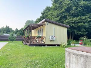 a small yellow house with a deck in a yard at Poilsio namelis po juodalksniais (Nemirseta) in Palanga