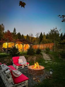 a fire pit in a yard with two chairs and a couch at Kenzo Chalet in Porumbacu de Sus