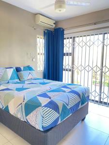 Un dormitorio con una cama con un edredón azul y blanco. en 1 Kiahuna, en Durban
