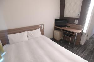 a bedroom with a bed and a desk with a computer at Washington R&B Hotel Hachioji in Hachioji