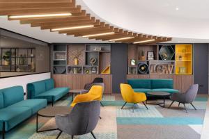 a waiting room with blue and yellow chairs and tables at Holiday Inn London Gatwick - Worth by IHG in Crawley