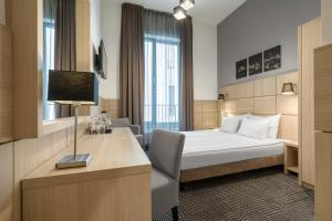 里加Wellton Centrum Hotel & SPA的一间配有床和书桌的酒店房间