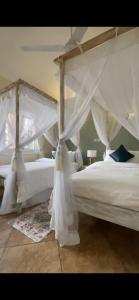 two beds with white drapes in a bedroom at Bamburi Beach Villa in Mombasa