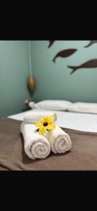 a towel with a yellow flower on top of a bed at Suítes e Chalé Colibri - Passarim Hospedagem in Cumuruxatiba