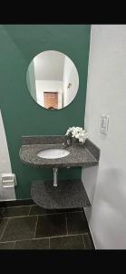 a bathroom with a sink and a mirror at Suítes e Chalé Colibri - Passarim Hospedagem in Cumuruxatiba