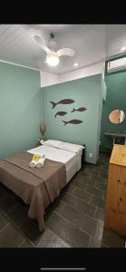 a bedroom with a bed with fish on the wall at Suítes e Chalé Colibri - Passarim Hospedagem in Cumuruxatiba