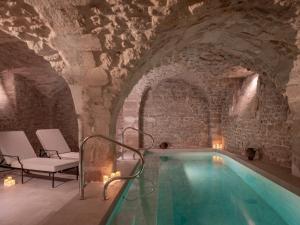 a swimming pool in a cave with a stone wall at Hotel Madeleine De Senlis in Paris