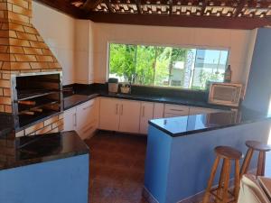 una cucina con mobili bianchi e una grande finestra di Espaço Portal Azul a Casa Branca