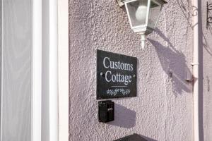 a sign on the side of a building with a street light at Customs Cottage in Teignmouth
