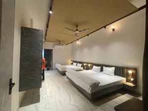 a hotel room with two beds and a mirror at Dhruvtara Farms in Jabalpur