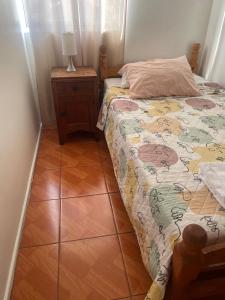 a bedroom with a bed and a table with a lamp at DepartamentoSantaInes in Viña del Mar