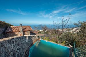 a stone wall with a blue pool in front of a house at Finca Rural House Tenerife Relax in Santa Úrsula