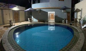 a large blue swimming pool with umbrellas around it at Pousada e Hostel Camboinha in Cabedelo